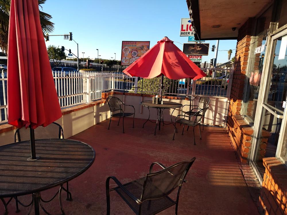 Patio at Brito's with metal tables and red umbrellas
